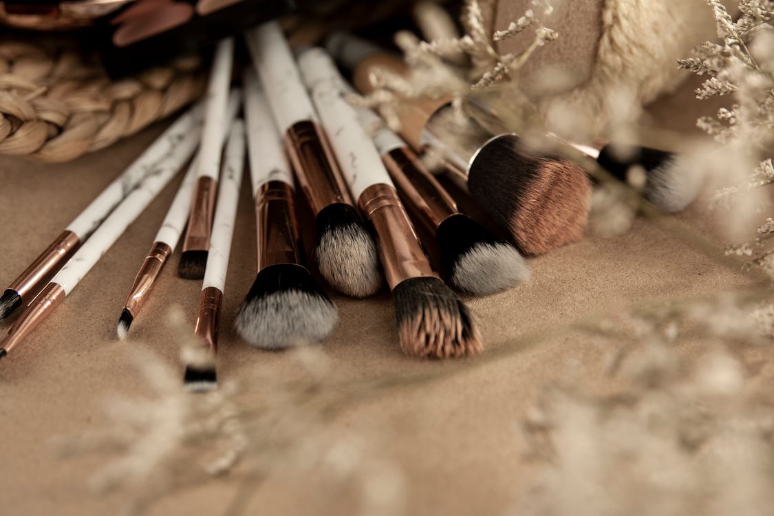 Brochas de maquillaje de distintos tamaños sobre una mesa beige