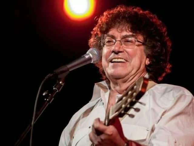 Piero cantando con su guitarra en un concierto