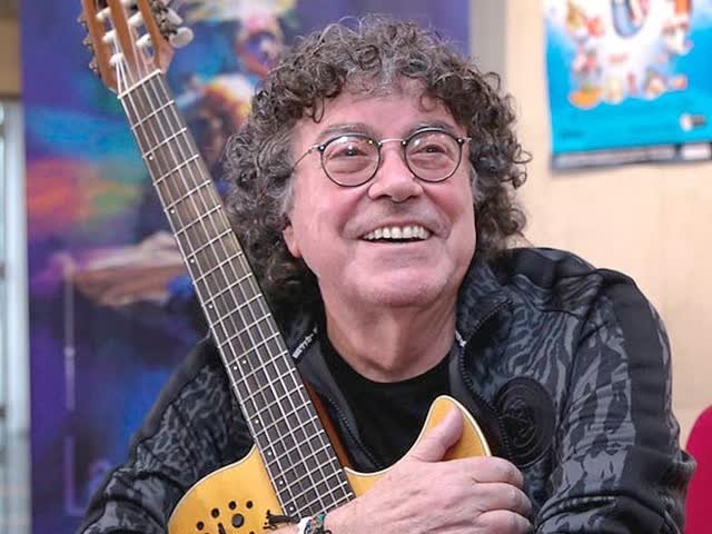 Piero sonriente abrazando su guitarra
