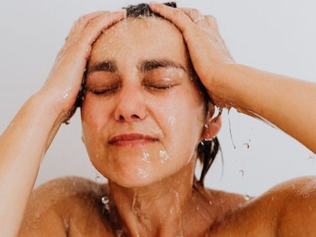 Mujer duchándose con agua tibia para no resecar la piel