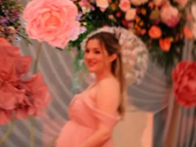 Melenie Carmona con vestido rosa y su pancita en su baby shower, entre flores gigantes