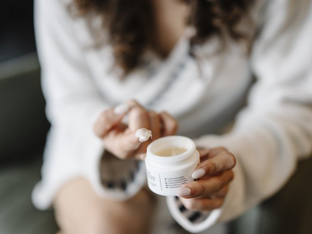 Mujer con crema hidratante en las manos