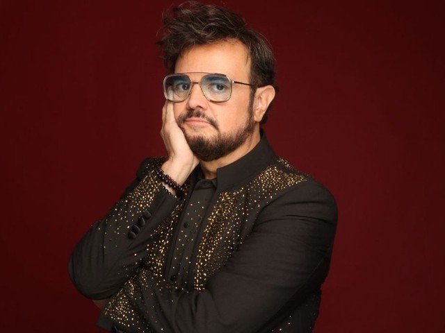 Aleks Syntek posando sobre fondo rojo